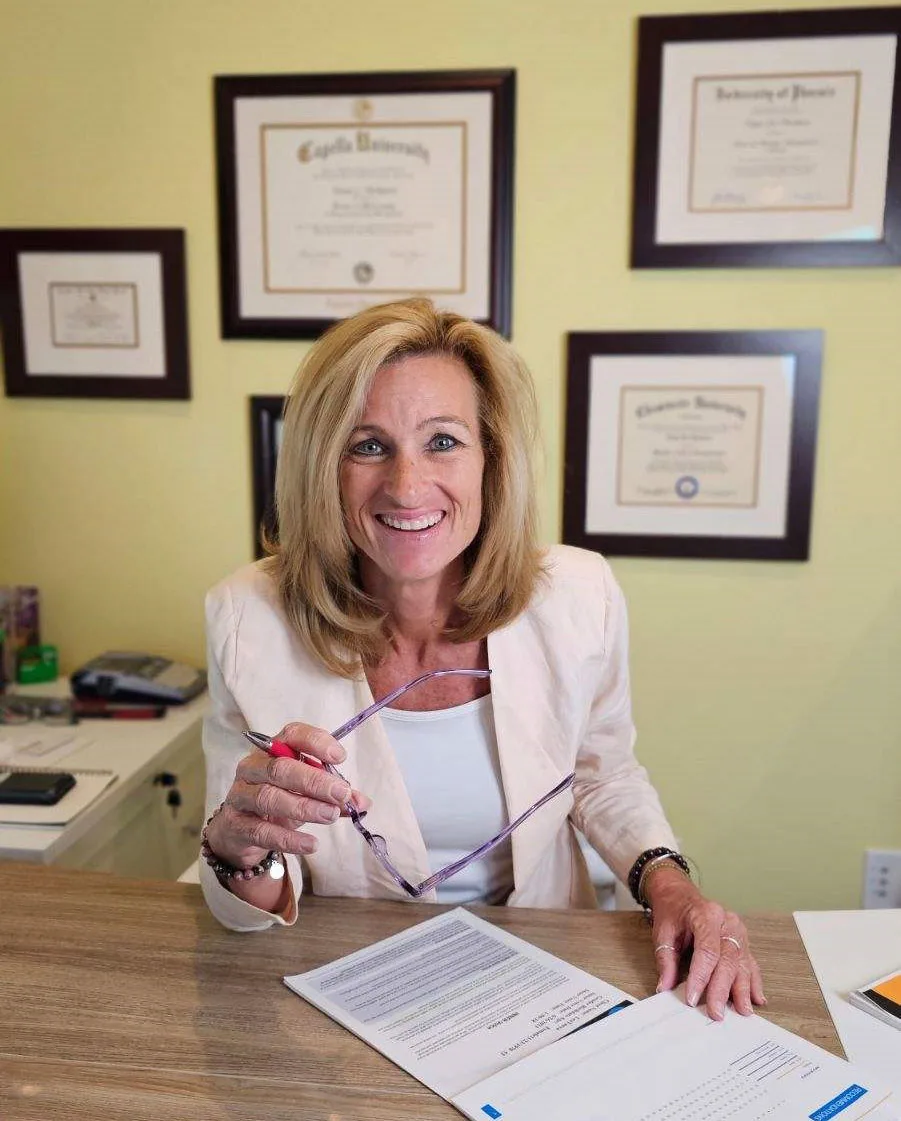 Dr. Tanya Lea at her desk, framed degrees on the wall behind her