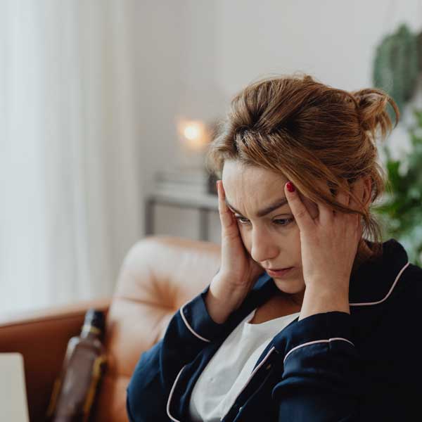 A woman sitting with her fingers pressed to her temples, eyes down.