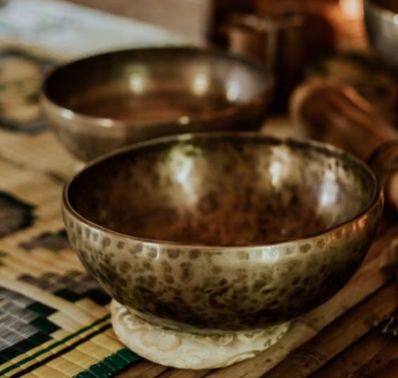 A hammered brass singing bowl on a woven mat, soft in warm light